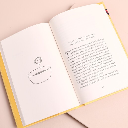 Open page inside Ramen Makes Us Complete book showing line drawing and essay text