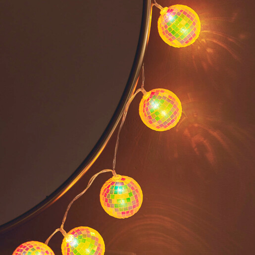 Close-up of illuminated mosaic ball string lights hanging along a round mirror
