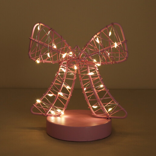 Pink wire bow table light illuminated with warm glowing fairy lights