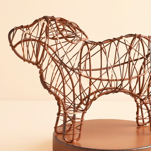 Close up of metal wire dog sculpture wrapped with fairy lights