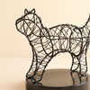 Close-up of black wire cat light showing wrapped fairy lights