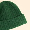 Close-up view of the rich forest green ribbed knit texture and fold-over cuff