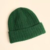 Forest green ribbed knit beanie hat laid flat on a neutral background