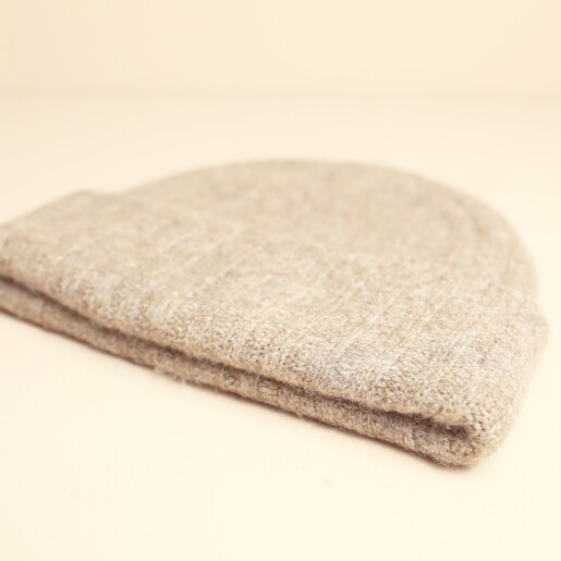 Side view of folded neutral ribbed beanie hat
