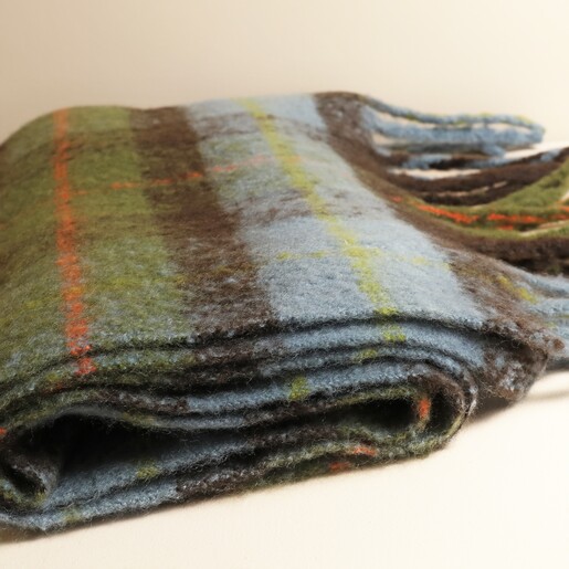 Close-up of folded green and orange tartan winter scarf fabric texture