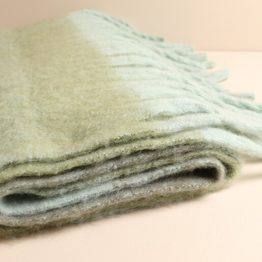 Close up of folded soft brushed green winter scarf with fringed trim