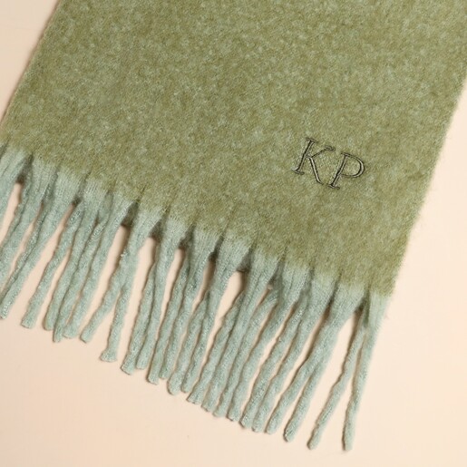 Close up of mint green winter scarf with embroidered initials KP above fringe