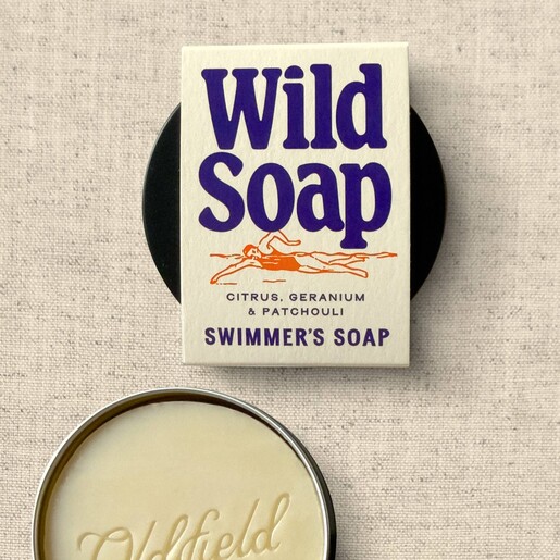 Wild swimmer's citrus and patchouli soap bar open beside its travel tin