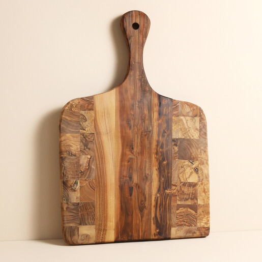 Rustic olive wood checkered serving paddle standing upright against a neutral wall