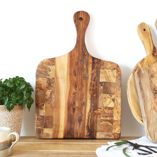 Olive wood checkered serving board styled on a tabletop with a plant and mug