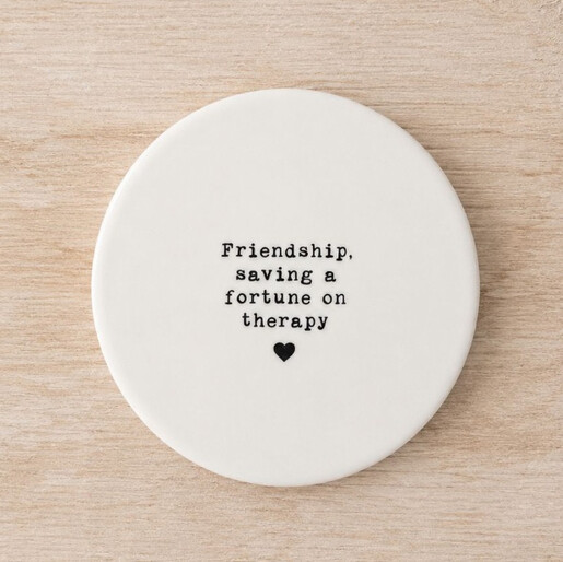 Round white ceramic coaster with black stamped quote about friendship and a heart motif