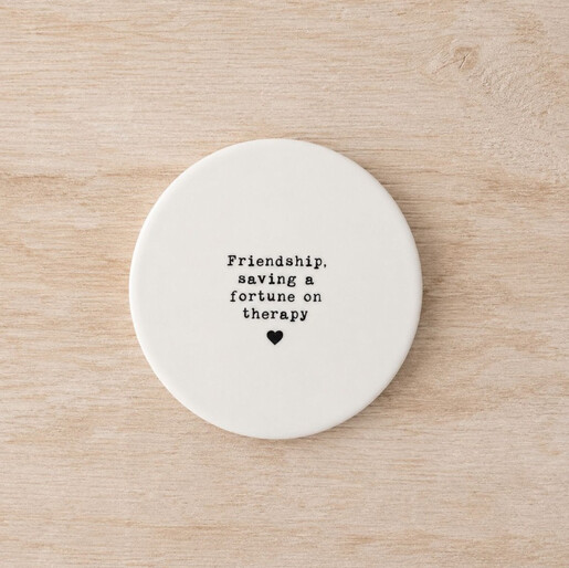 White circular ceramic drink coaster on a natural light wood background
