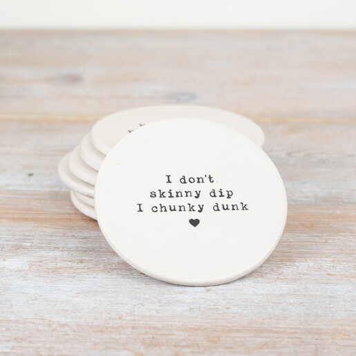 Round white porcelain drink coaster with playful chunky dunk quote on wooden surface