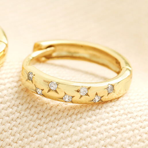 Close up of gold scattered star huggie earring with sparkling cubic zirconia crystals