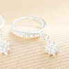 Close-up of a sterling silver huggie earring with cubic zirconia star charm.