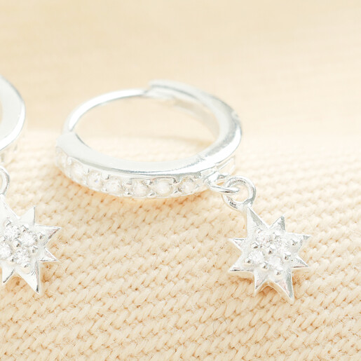 Close-up of a sterling silver huggie earring with cubic zirconia star charm.