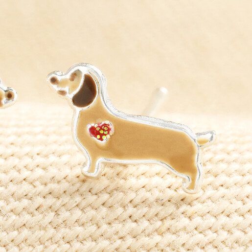 Close-up of a sterling silver enamel sausage dog stud earring with red heart motif