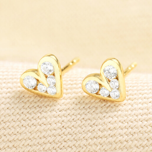 Pair of gold sterling silver crystal heart stud earrings on textured fabric