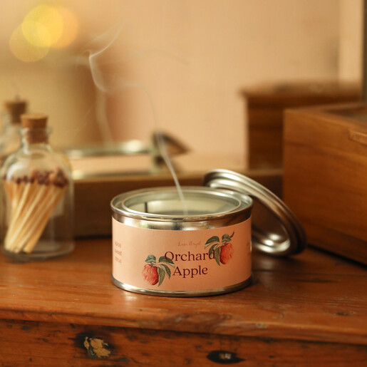 Extinguished Orchard Apple candle tin with smoke drifting from the wick