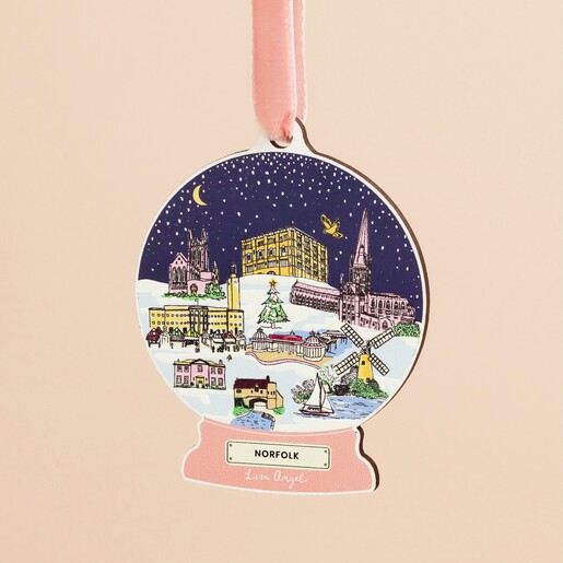 Close-up of wooden snow globe hanging decoration featuring illustrated Norfolk landmarks.