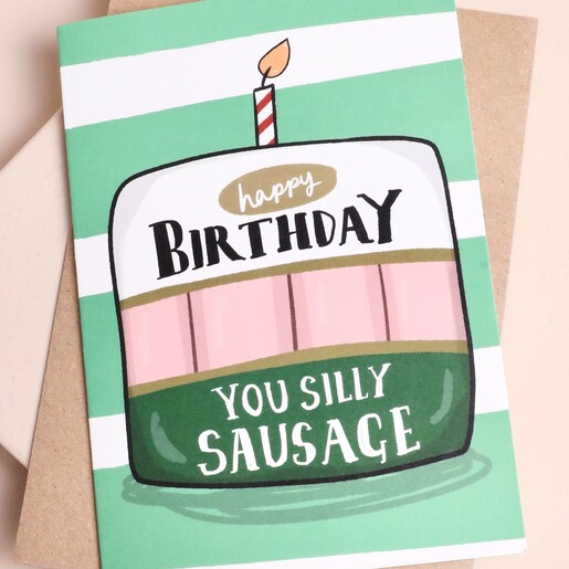 Close-up of the Silly Sausage birthday cake card on striped background
