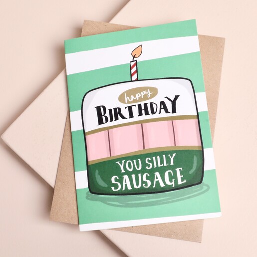 Silly Sausage birthday card featuring an illustrated cake with a kraft envelope