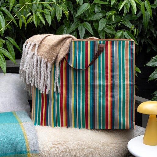 Rex colourful retro striped jumbo storage bag with a fringed blanket draped over it