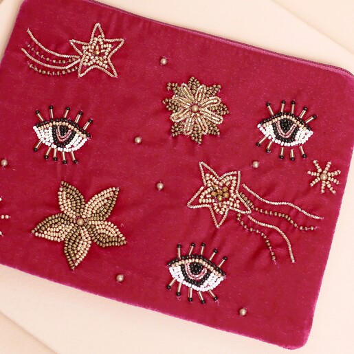 Close-up of beaded celestial eye and shooting star details on pink velvet pouch.