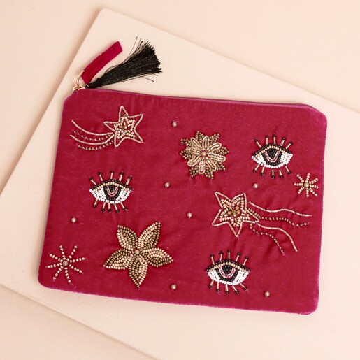 Pink velvet pouch embellished with beaded celestial eye motifs, shooting stars and a tassel zip.