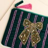 Close-up of gold beaded bow and pink stripes on forest green velvet pouch