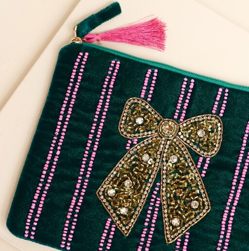 Close-up of gold beaded bow and pink stripes on forest green velvet pouch