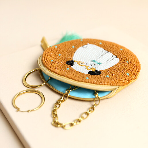 Open yellow beaded pug purse revealing bright turquoise interior lining with gold jewellery inside