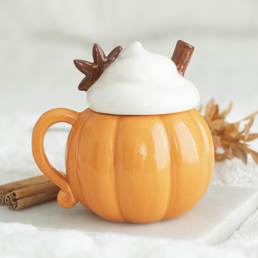 Ceramic orange pumpkin shaped mug with decorative whipped cream and cinnamon stick lid