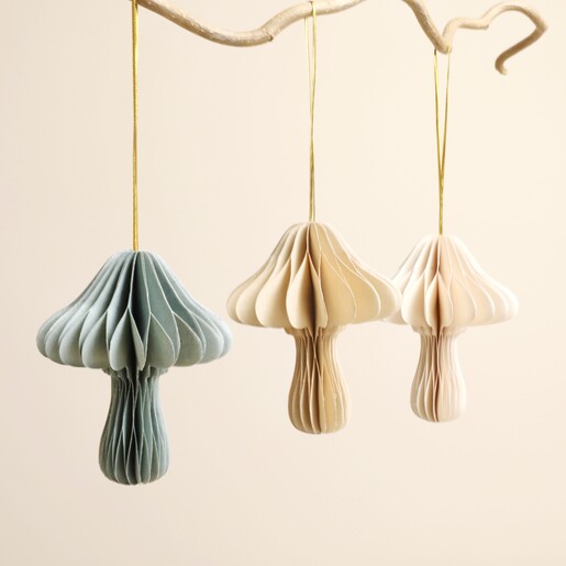 Three pleated paper toadstool decorations hanging from a rustic wooden branch