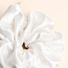 Close-up of the smooth gathered fabric on the white satin scrunchie