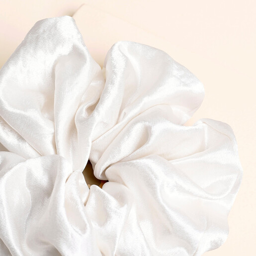 Close-up of the smooth gathered fabric on the white satin scrunchie