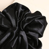 Close-up of the gathered black satin fabric on the oversized scrunchie.