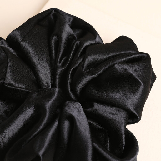 Close-up of the gathered black satin fabric on the oversized scrunchie.