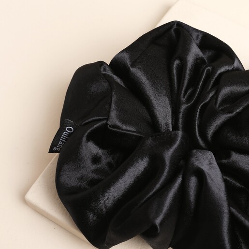 Close-up of the gathered black satin fabric on the oversized scrunchie.