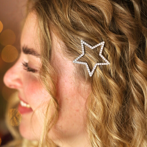 Side profile of woman wearing large silver crystal star hair clip in wavy blonde hair