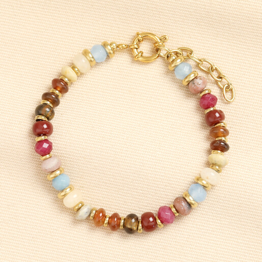 Gold beaded bracelet with multicoloured semi precious stones on cream fabric