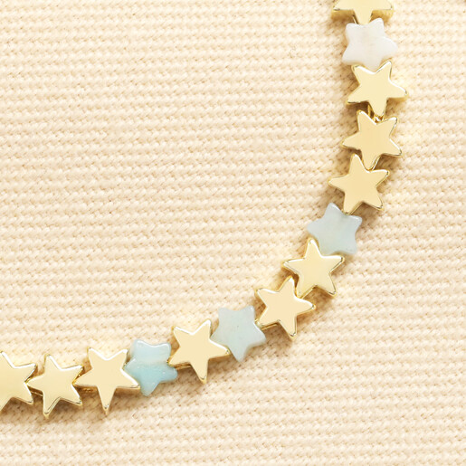 Close-up of gold and pastel turquoise star charms on delicate adjustable bracelet