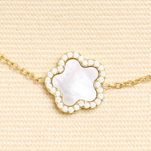 Close up of gold flower charm with pearlescent centre and cubic zirconia border