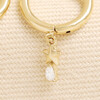 Close up of gold huggie hoop earring with star and crystal teardrop charm