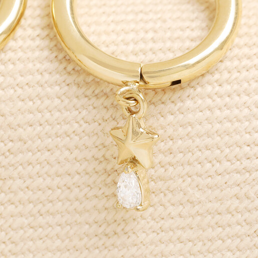 Close up of gold huggie hoop earring with star and crystal teardrop charm