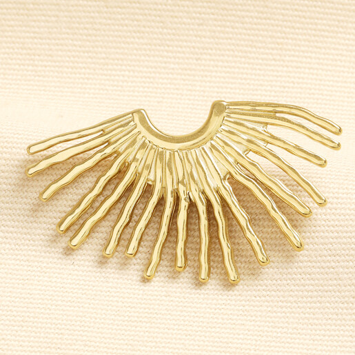 Close up of a gold stainless steel fan stud earring showing radiating rays