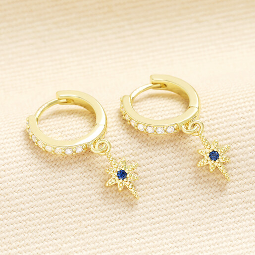 Pair of gold huggie hoop earrings with blue crystal star charms