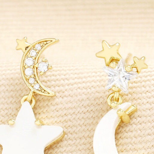 Close up of mismatched star and moon drop earrings with sparkling crystal accents.