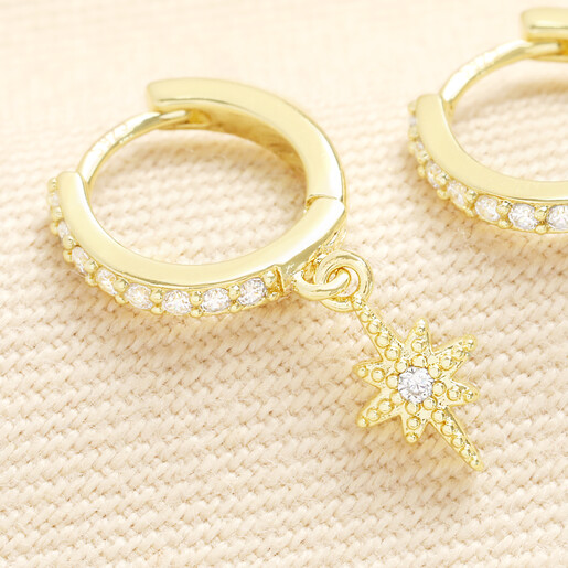 Close up of gold huggie hoop earring with crystal star charm