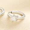 Close up of silver huggie hoop earring featuring star shaped cubic zirconia crystal